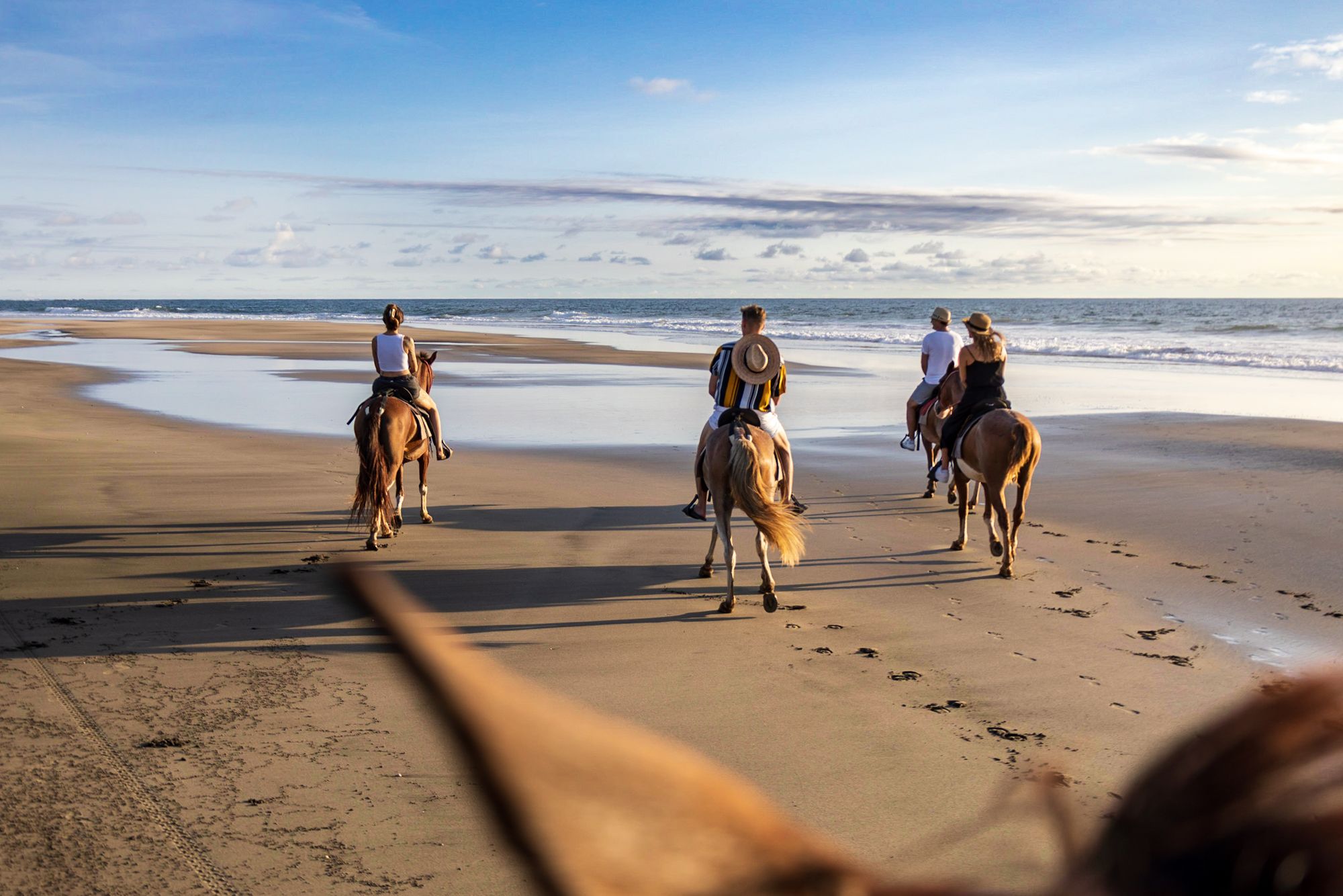 Horseback riding on the beach at sunset